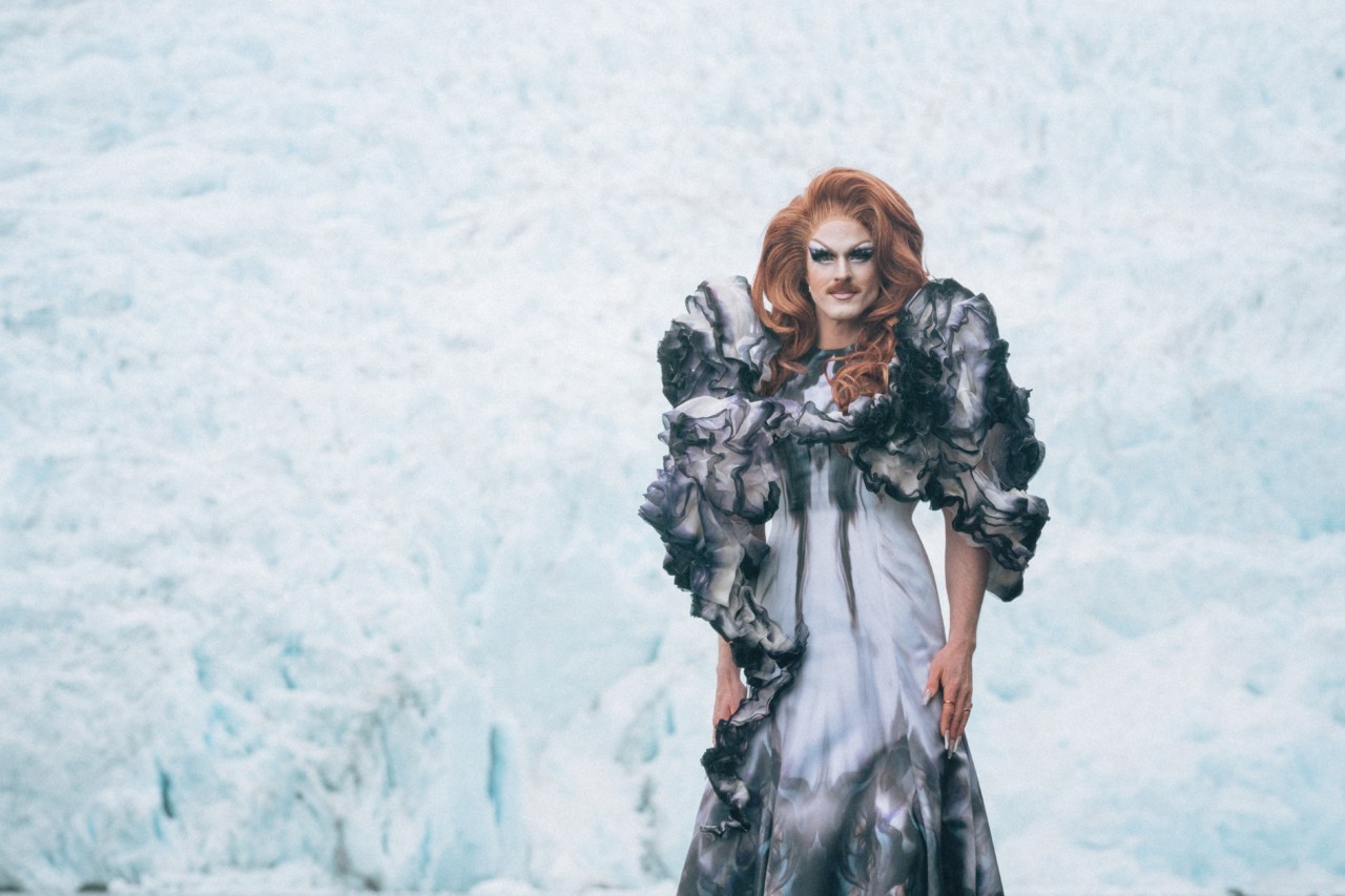 Pattie Gonia poses in front of an icy back drop.