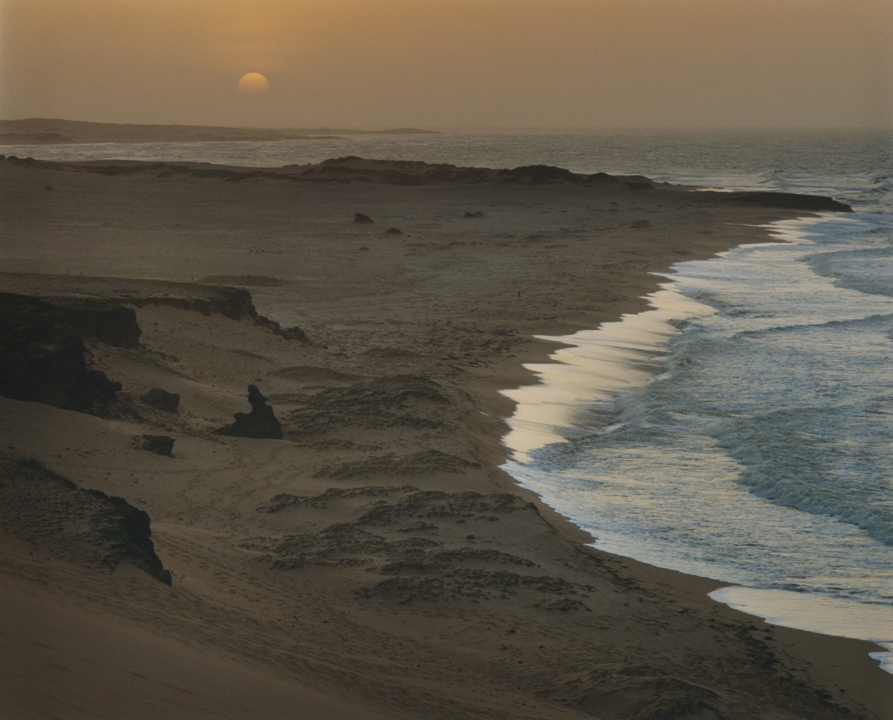 The sun sets along the coastline of a beach in Colombia.