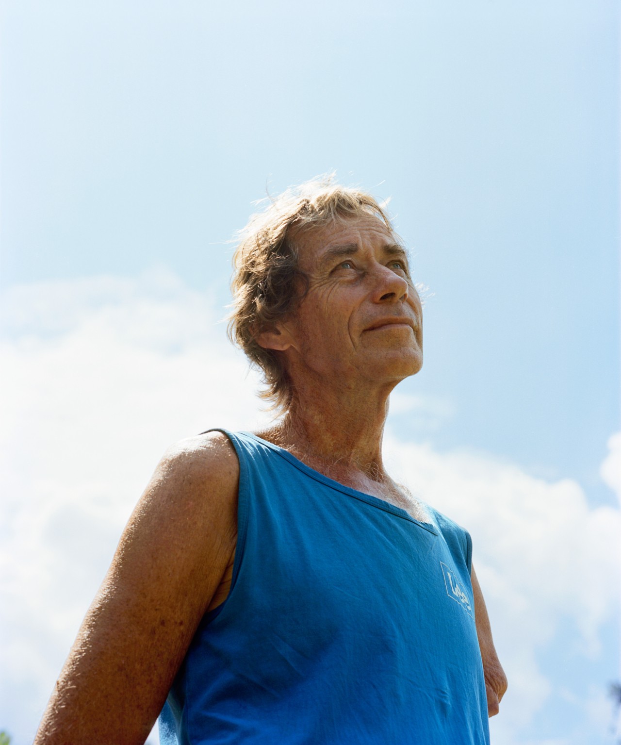 A person wearing a blue shirt in Auroville looks toward the sky.