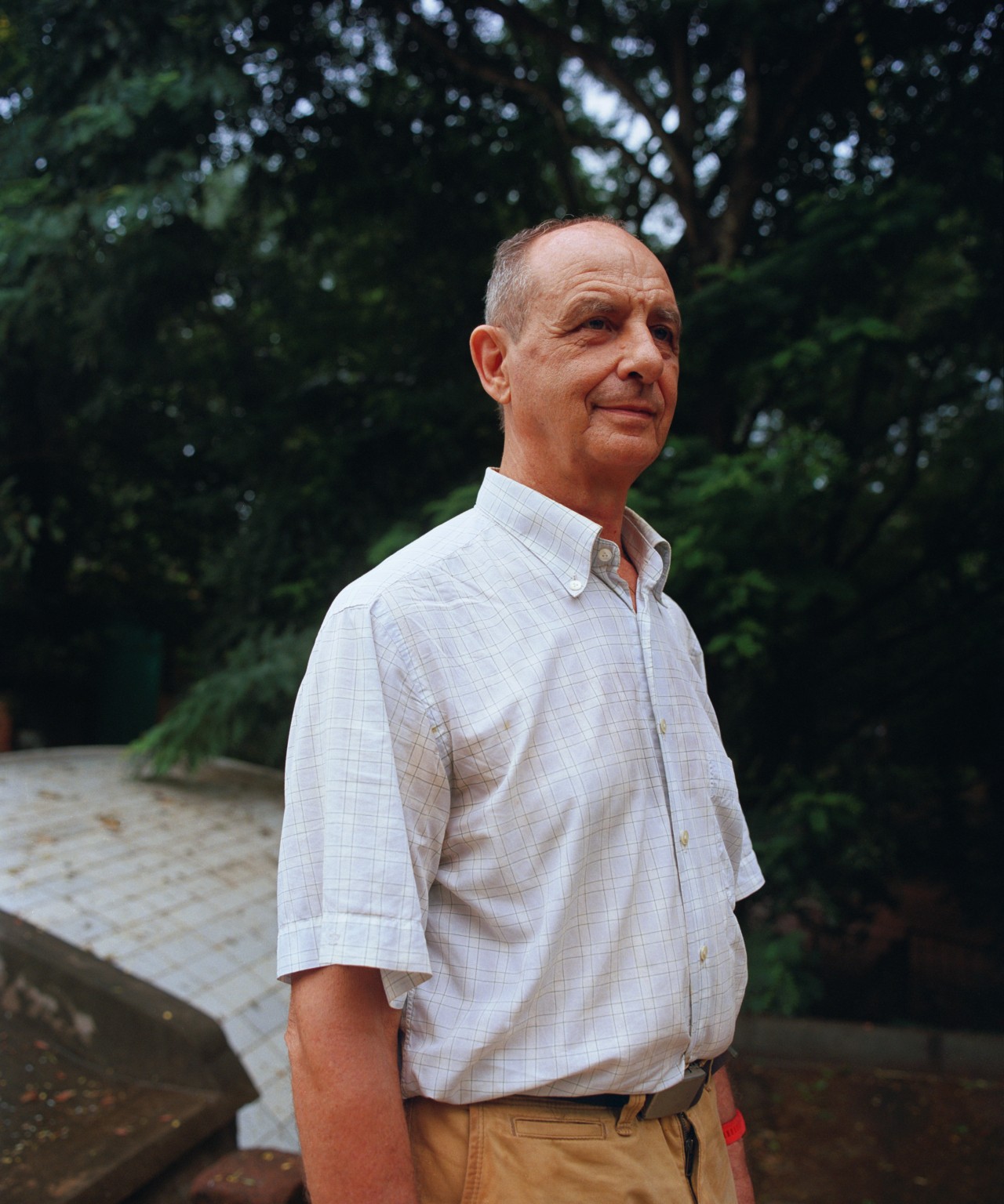 An older man wearing a collared shirt looks toward the distance.