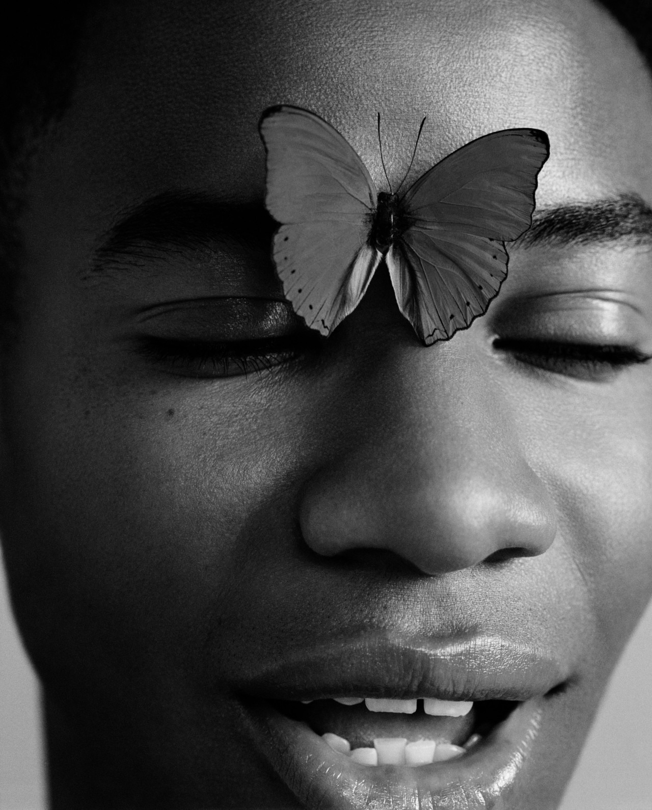 A butterfly rests on the forehead of a human.