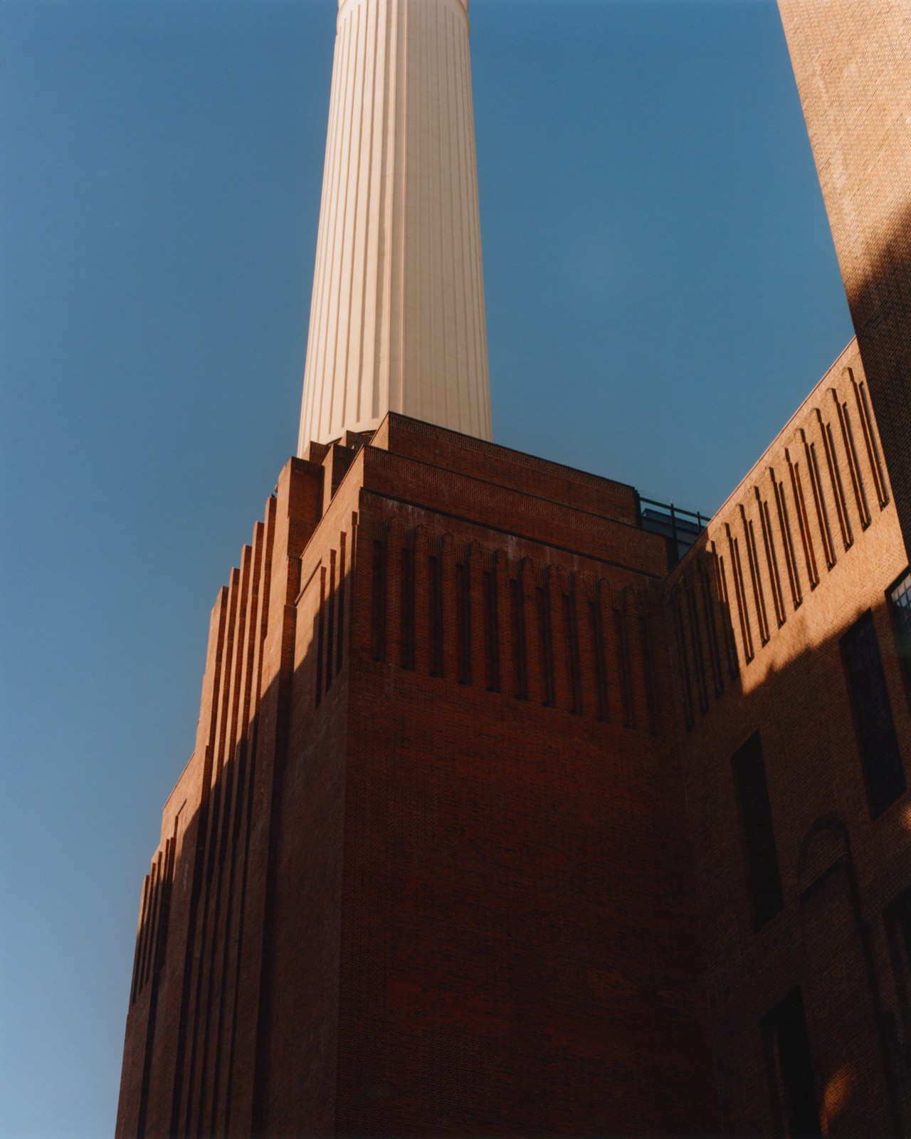 A white pillar sits on top of a brick red building.