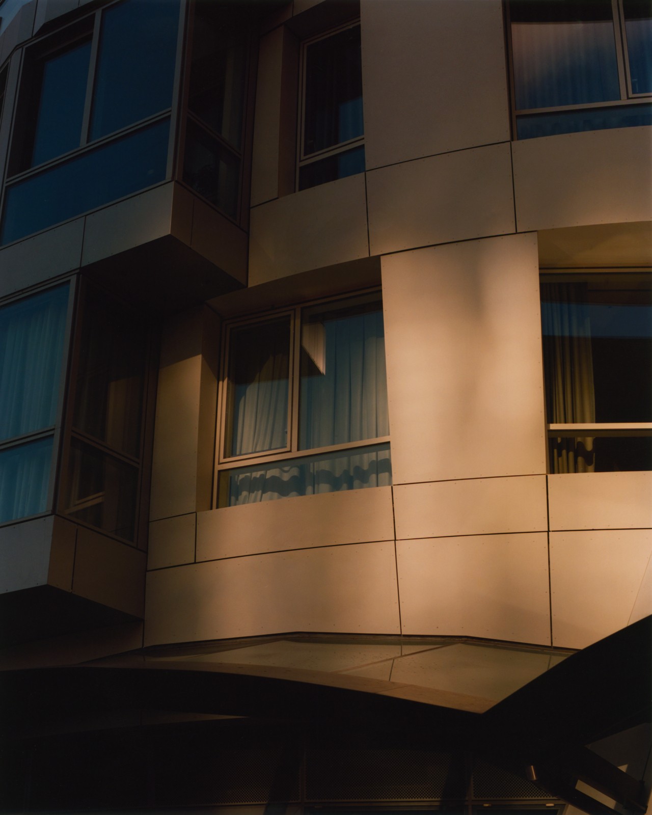 The side of a building reveals windows in the dusk.