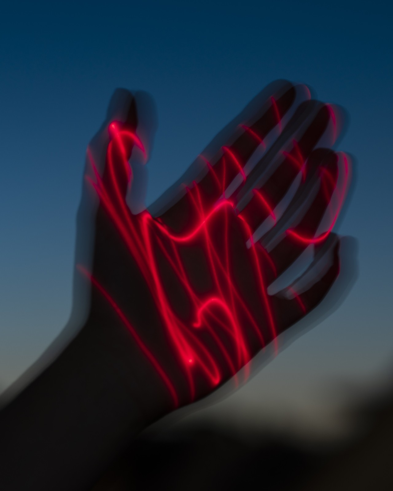 Red laser lights shine on a shadowed hand.