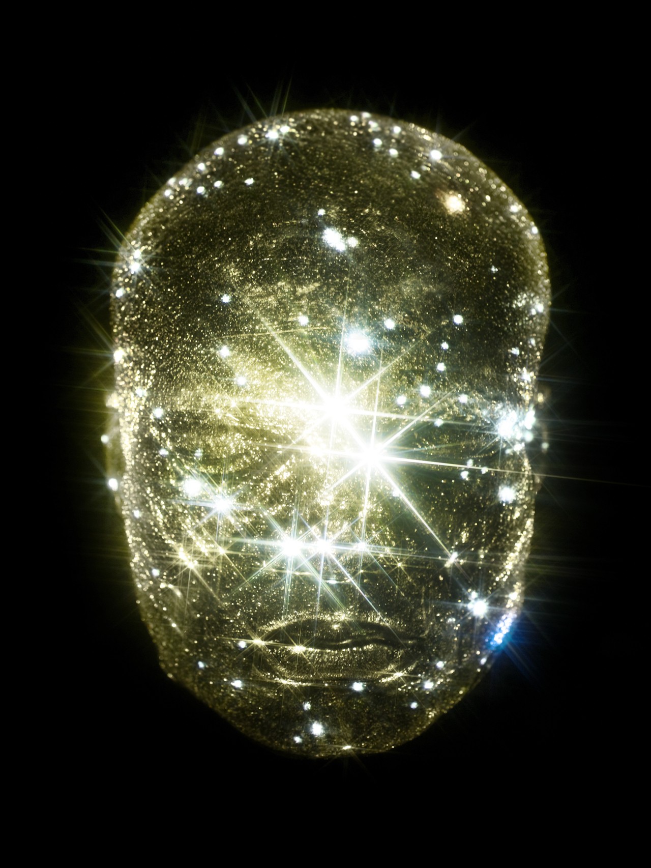 A transparent human head is filled wit shining star light.