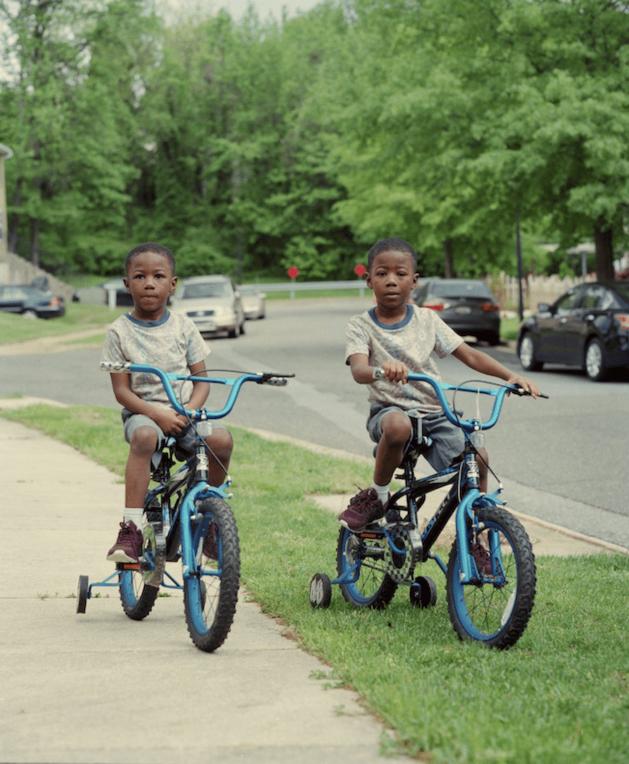 Young, twin black boys pose on identical bicycles in a Washington, D.C neighborhood.