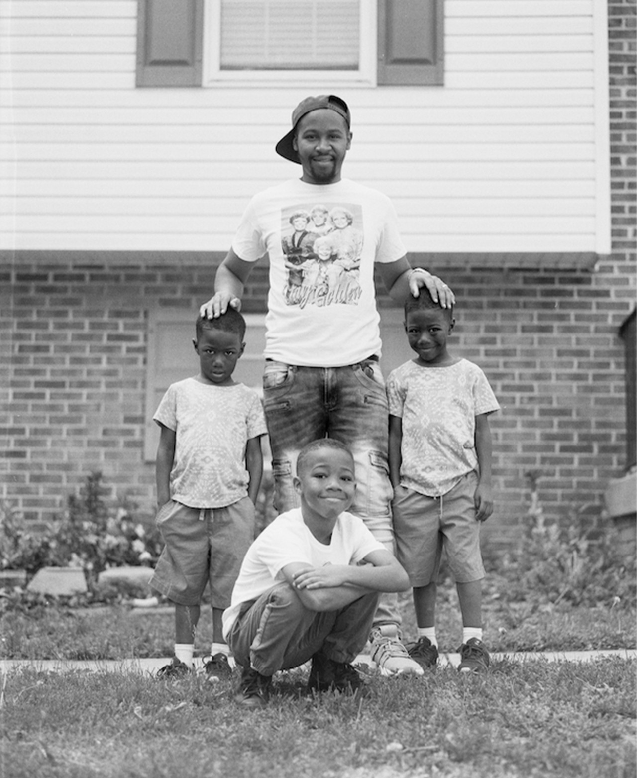 A young father poses with his three sons in front of a Washington, D.C home.