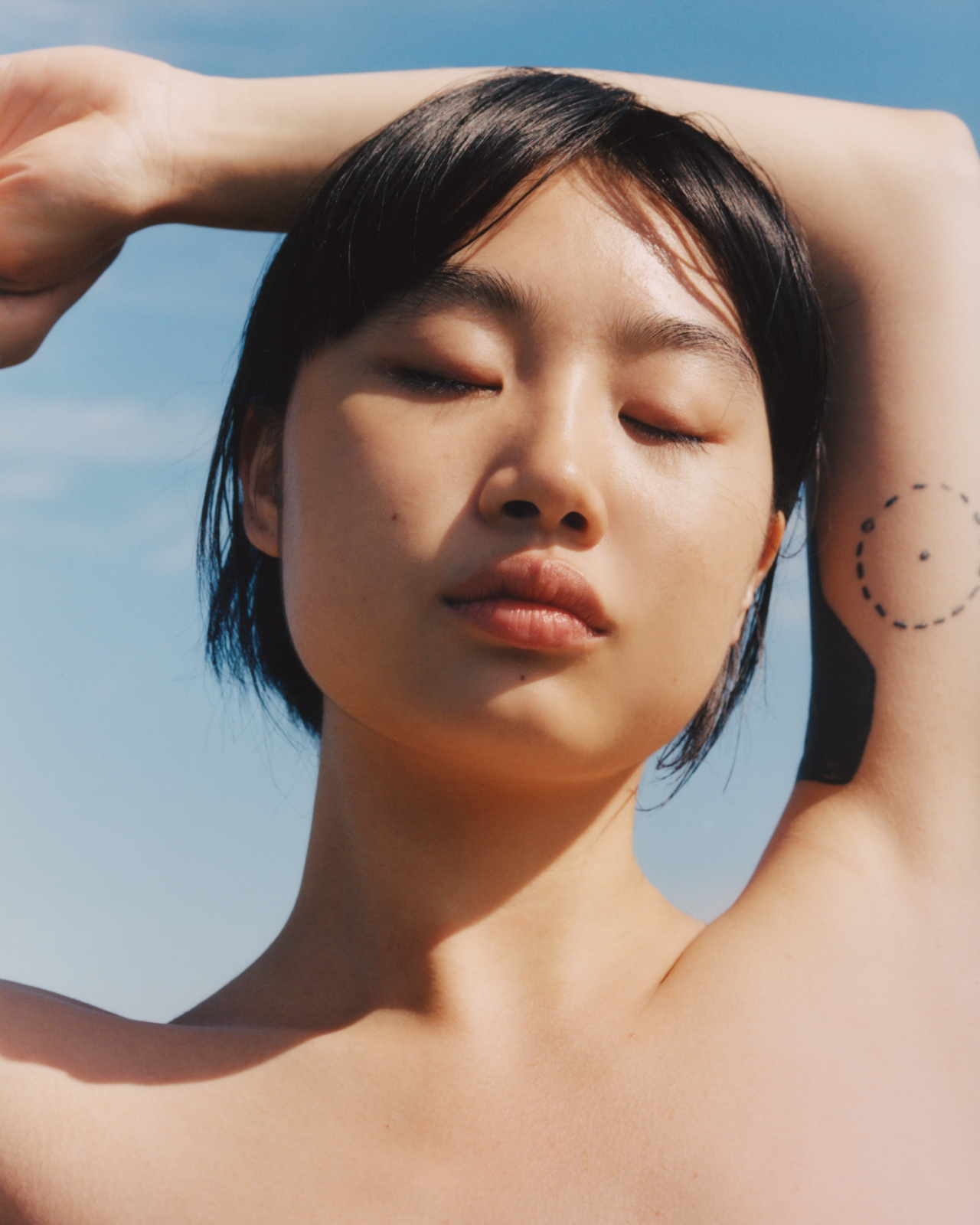 A profile of a model holding their arm above their head.