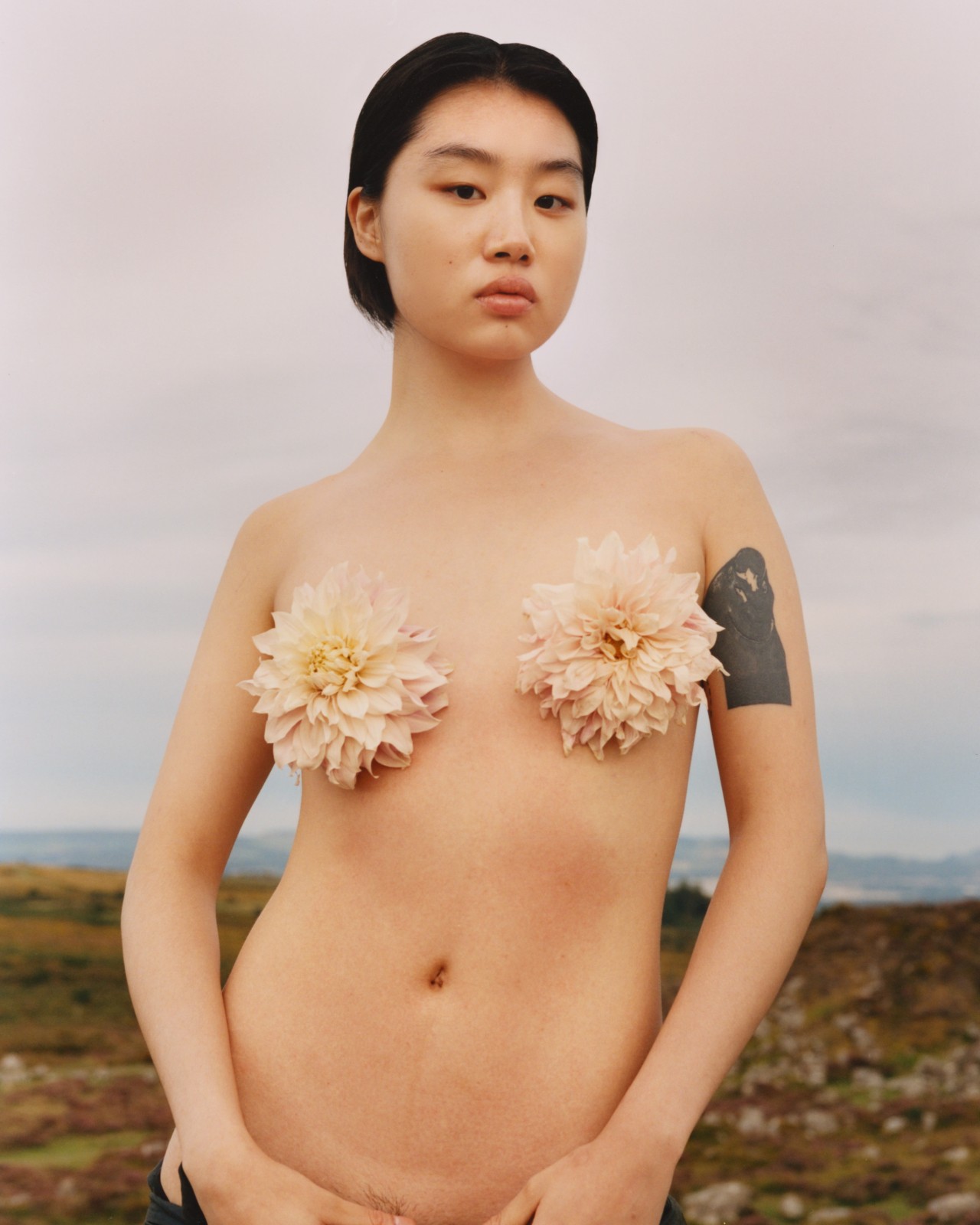 Two pink flowers cover the bare chest of a model.
