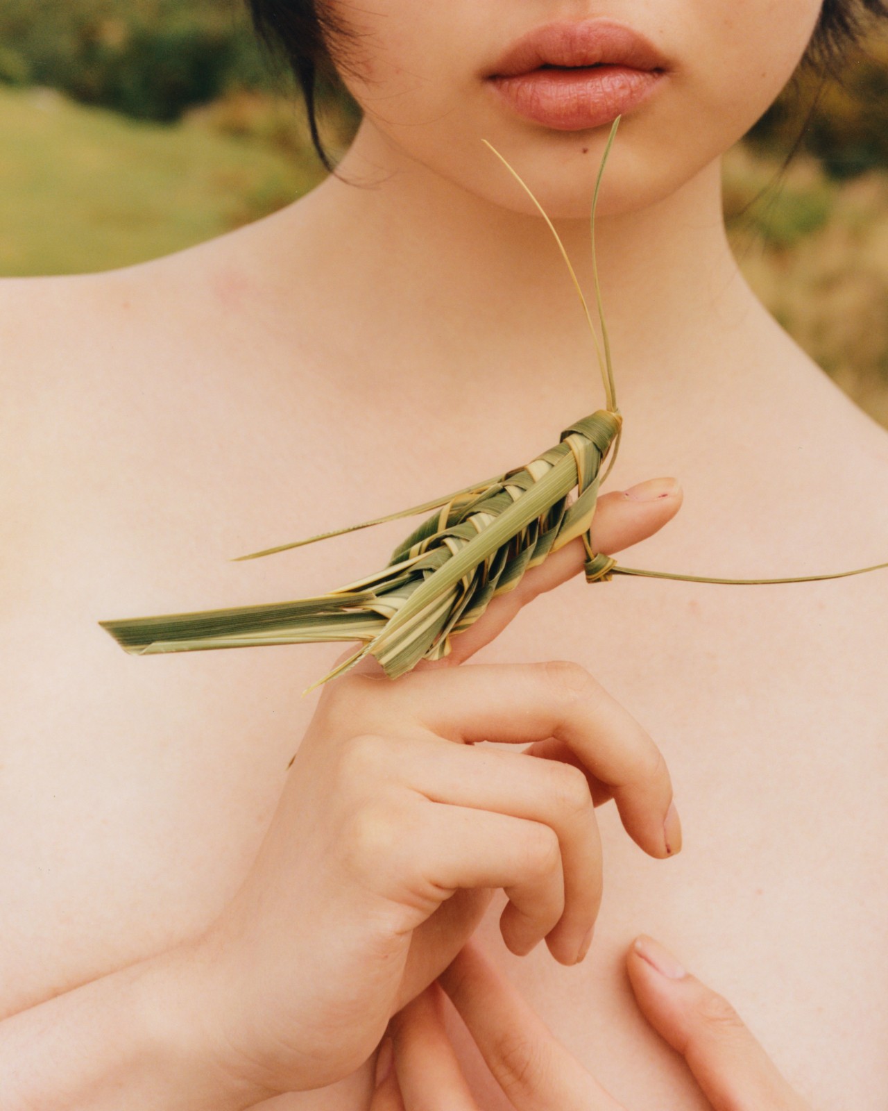 A locust made from bamboo leaves is tied around a model's finger.