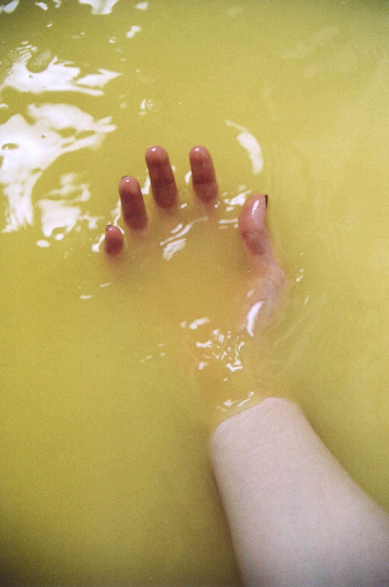 A hand is barely visible in murky yellow water.