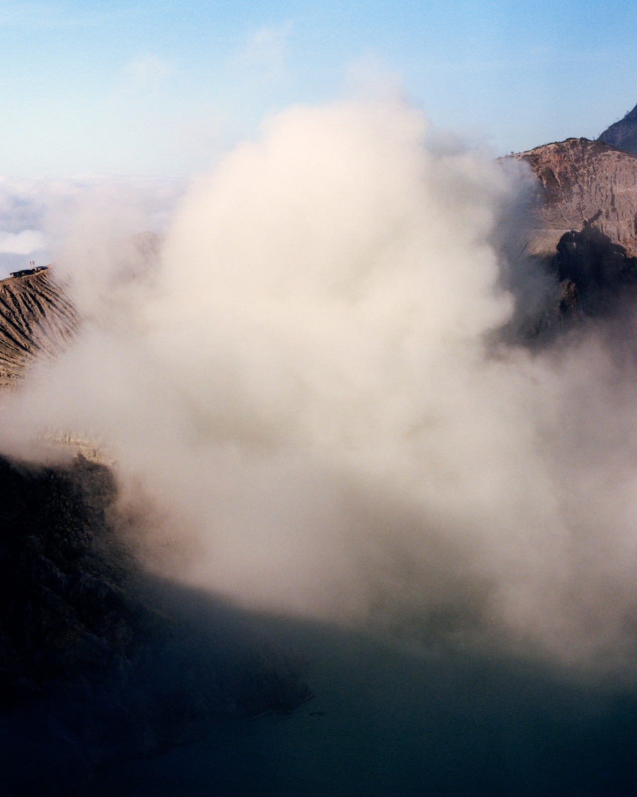 A large cloud of fog surrounds a mountain.