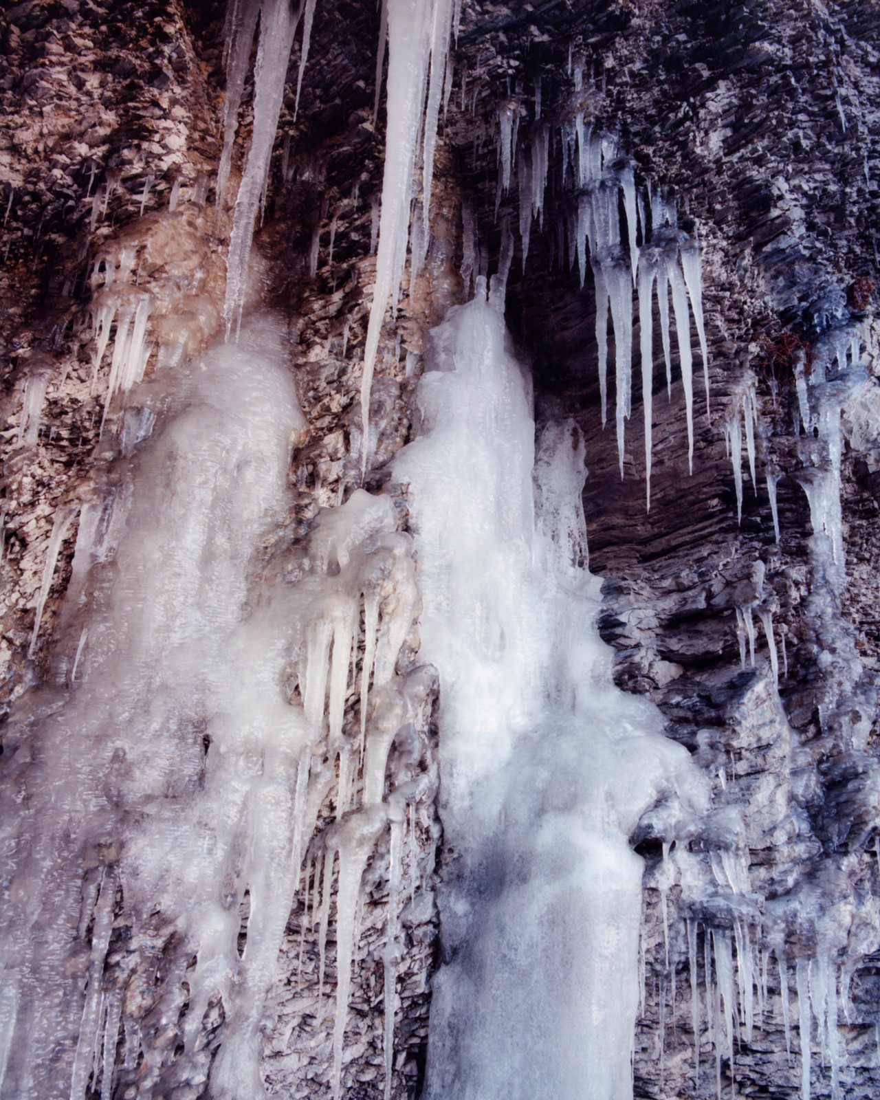 Icicles grows along the rocky walls of the inside of a cave.