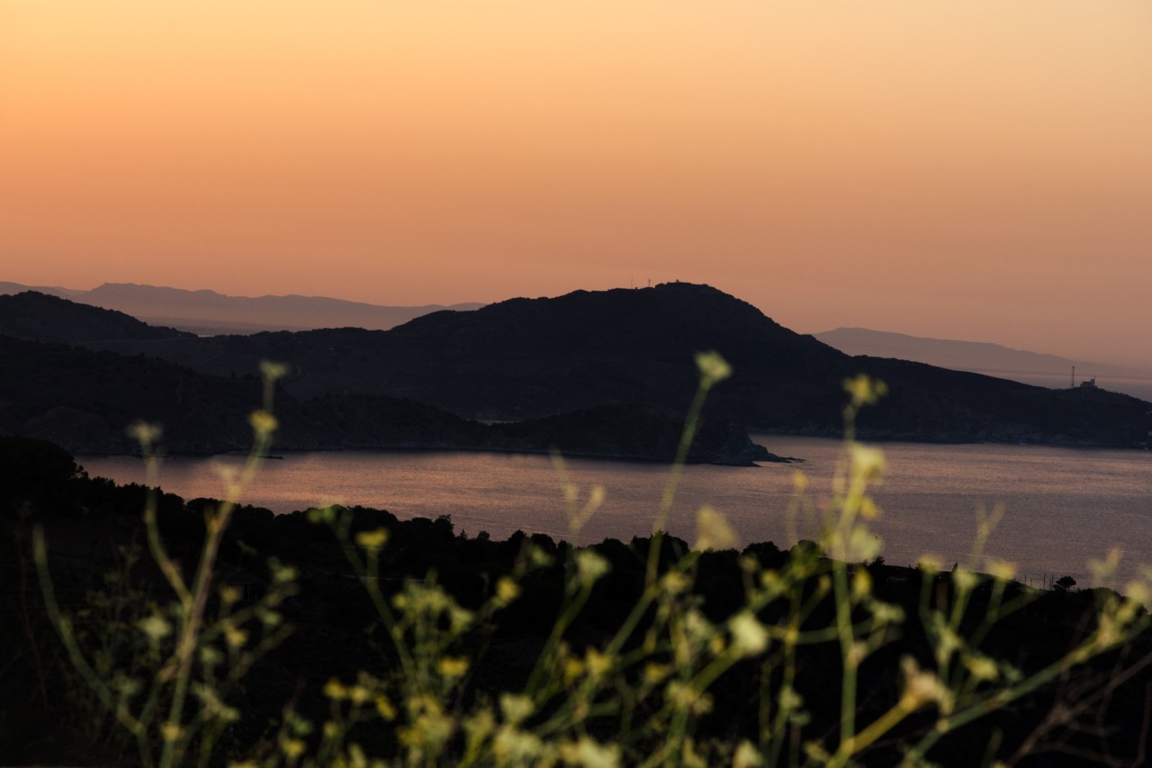 The sun sets behind distant mountains.
