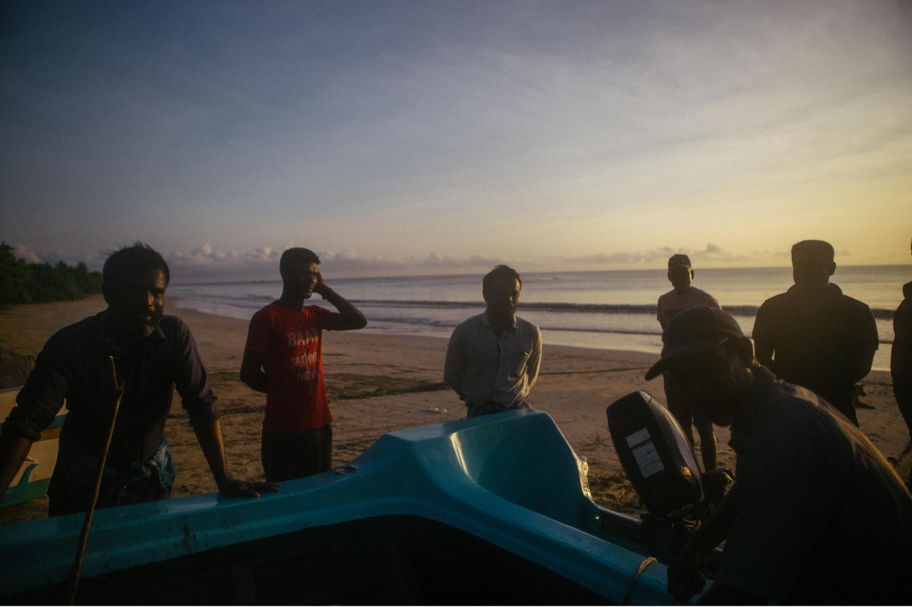 Fishermen haul a motorboat onto the sandbar on Pasikuda Beach, both an important fishing site and tourist destination.
