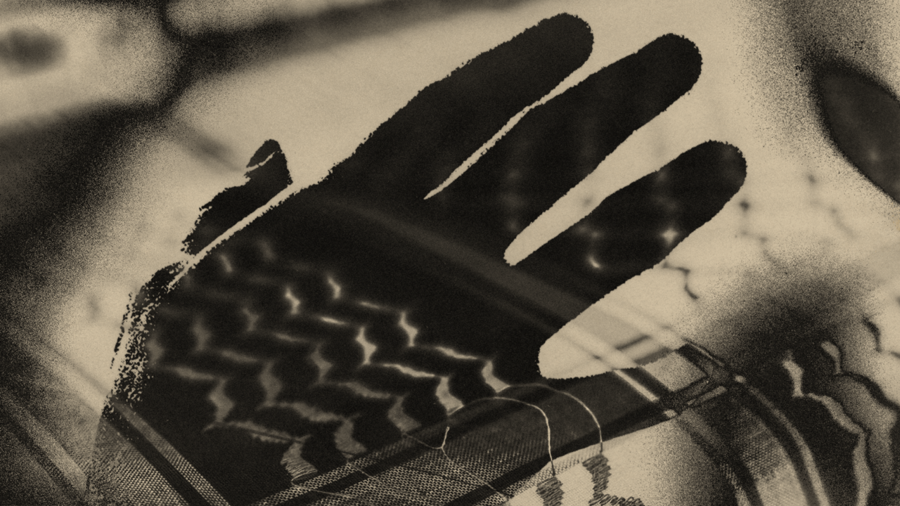 The translucent shadow of a hand hovers above the checkered pattern of a keffiyeh.