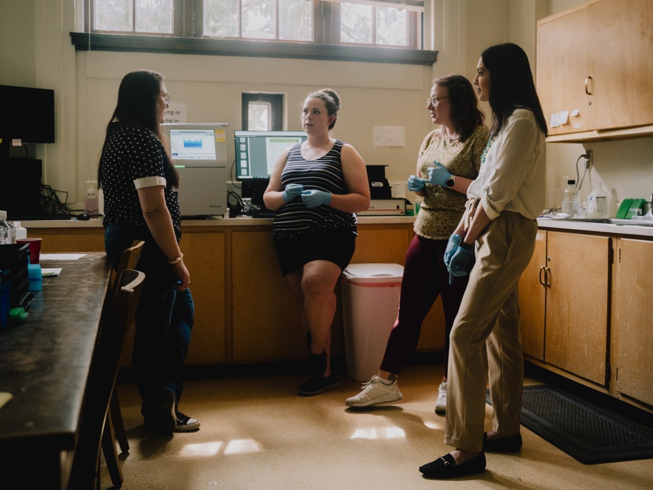 Four people talk amongst each other in a forensics lab.
