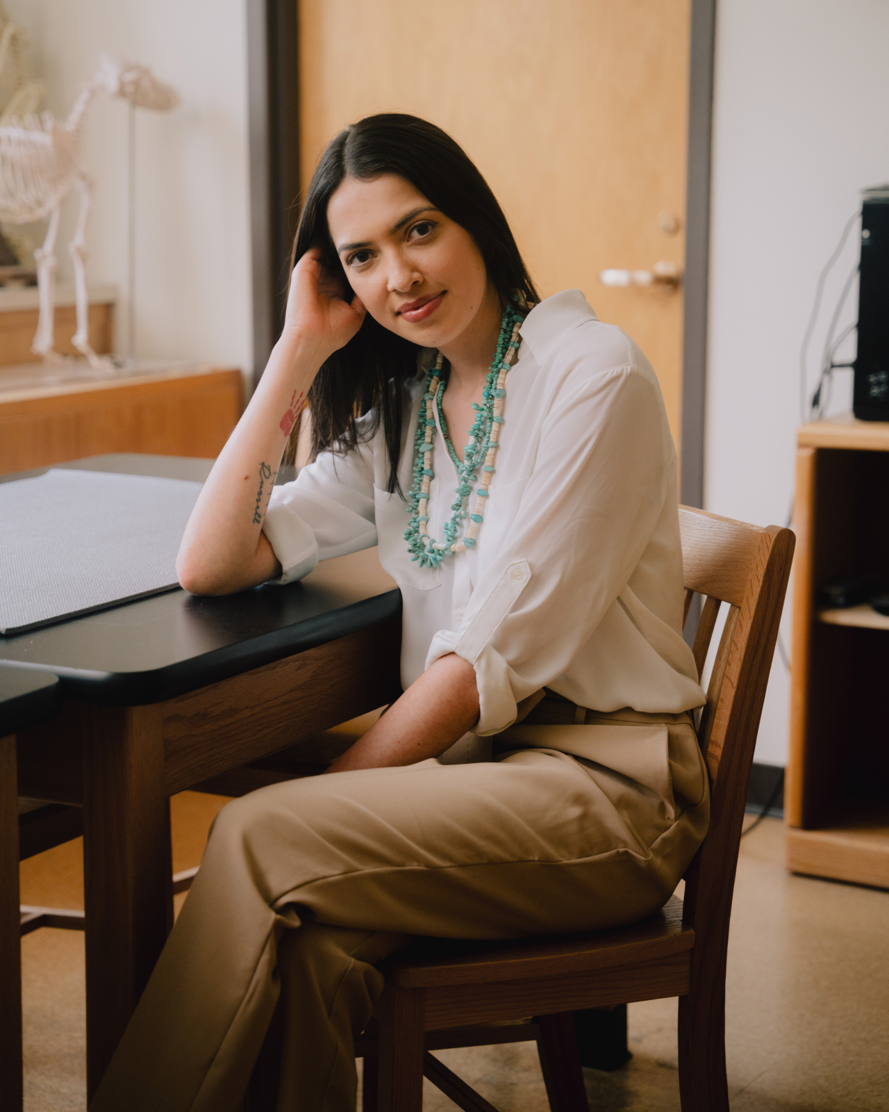 Haley Omeasoo, the founder of an Indigenous forensics lab in Montana sits at a desk.