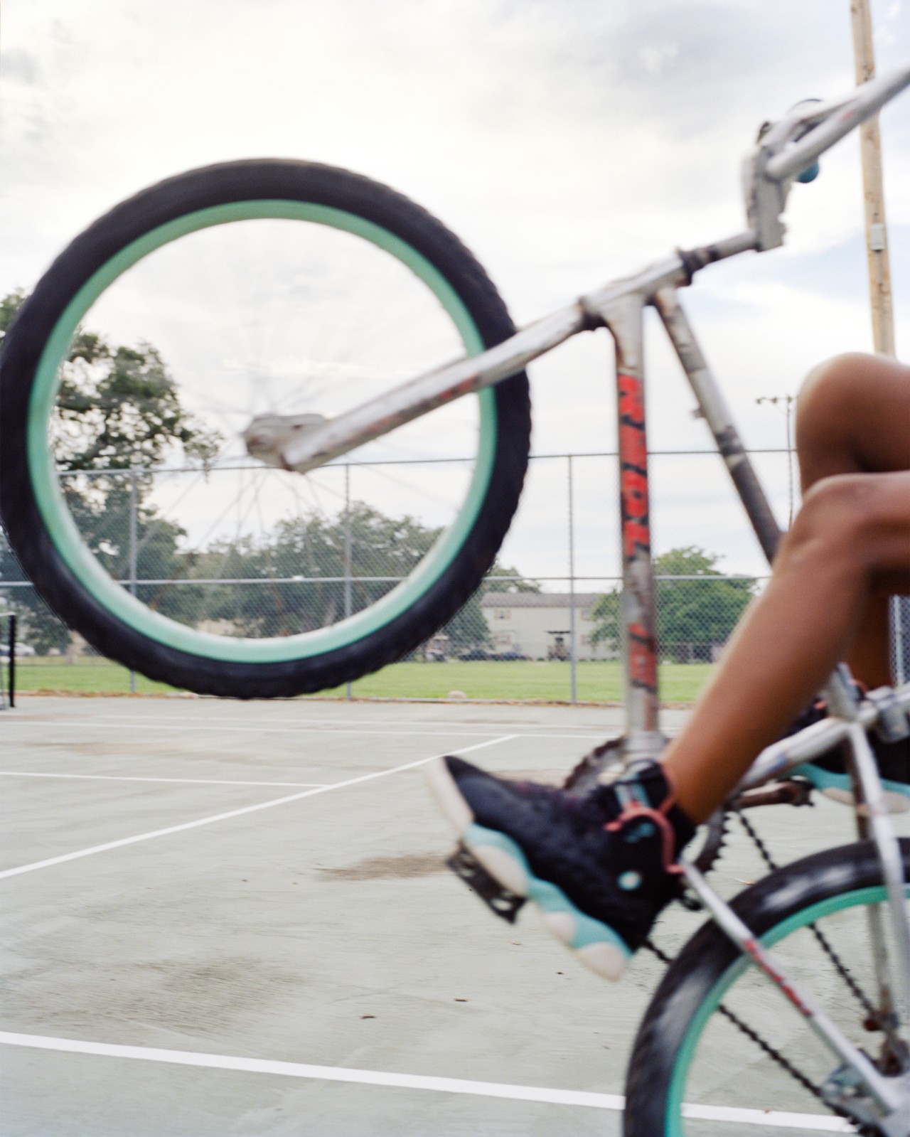 A child leans back on the rear wheel of a bicycle.