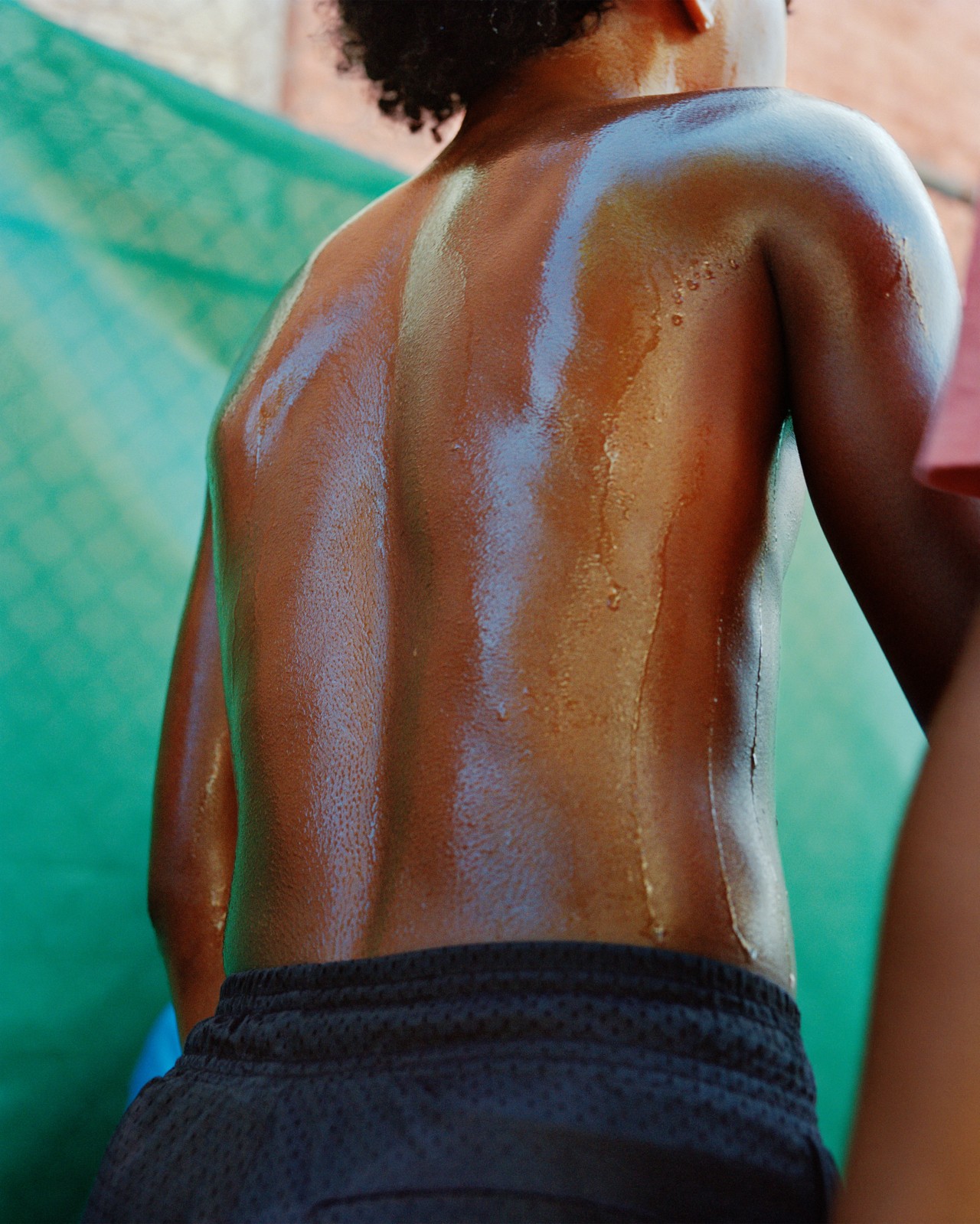 A boy's back is covered in sweat on a hot day in New Orleans.