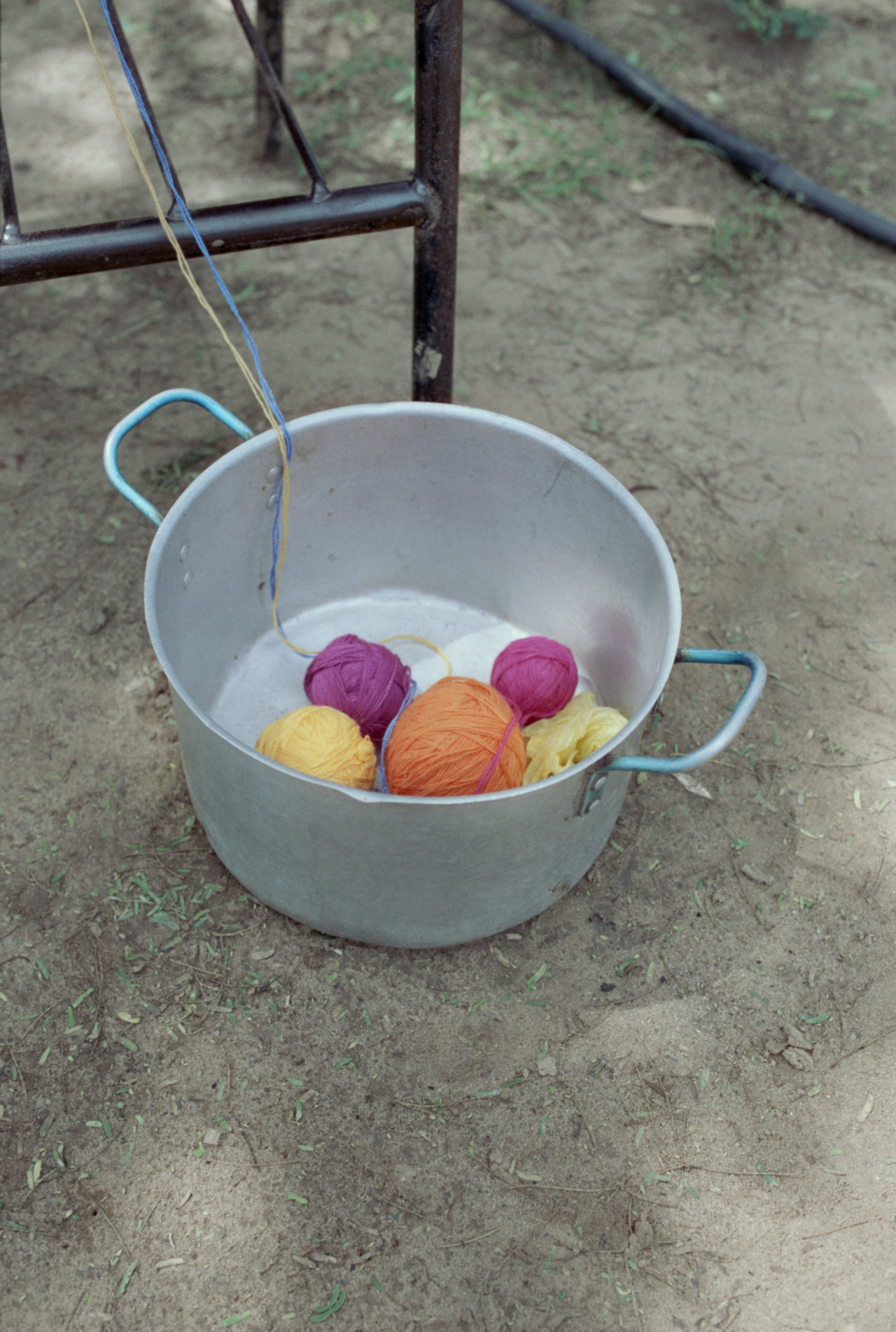 Several balls of different colored yard sit in a metal pot on the ground in Colombia.