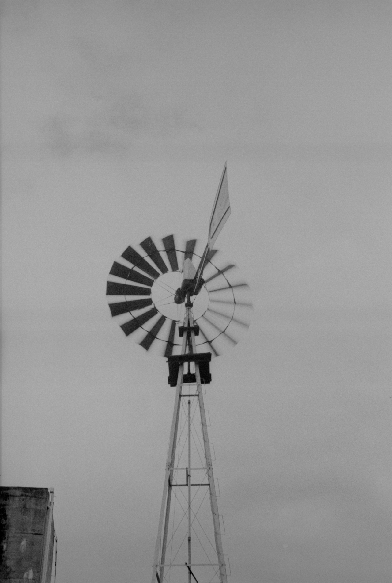 A windmill spins in front of a cloudy backdrop.