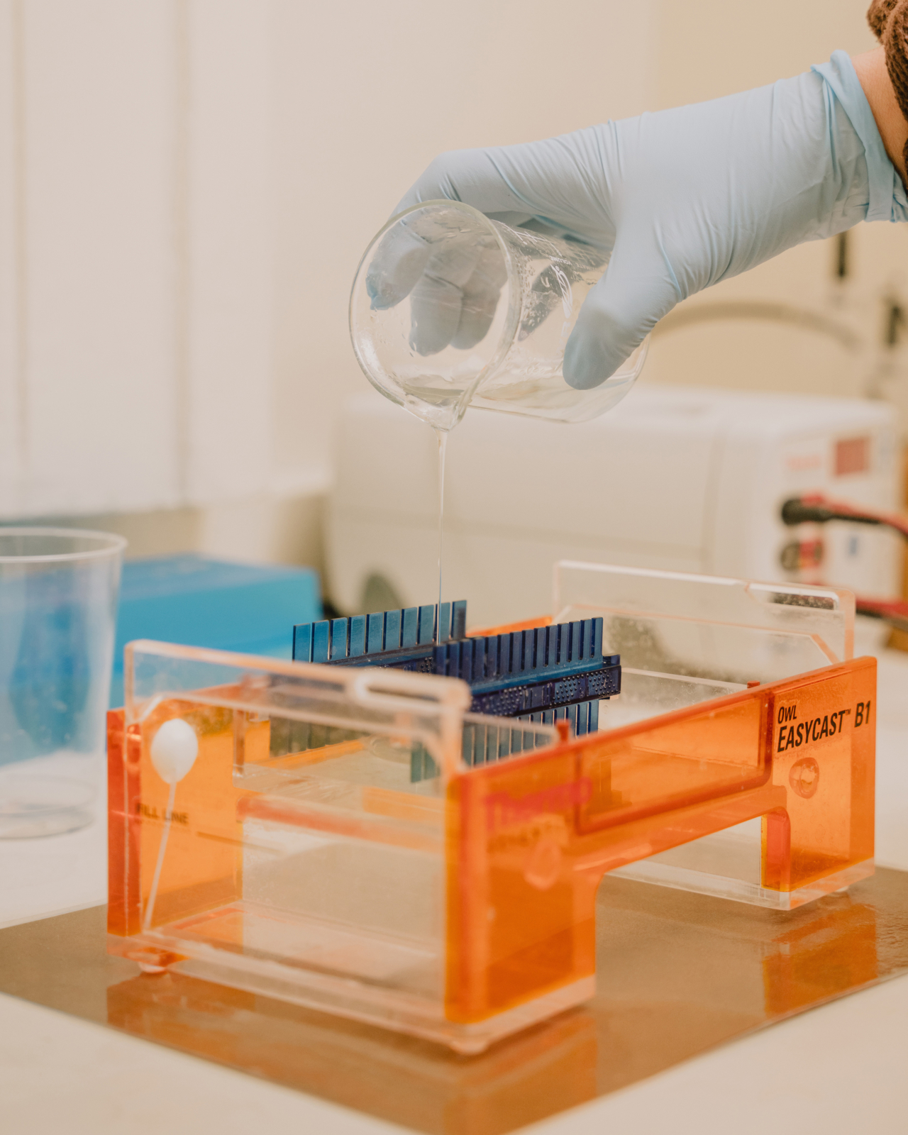 A scientist pours liquid from a beaker into a DNA kit in a forensics lab.