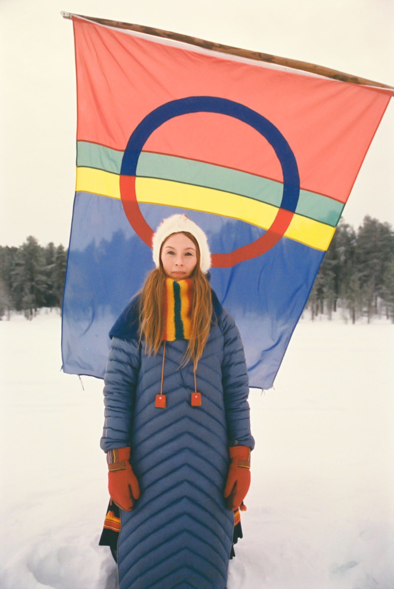 Sofia Jannok stands straight in front of a flag.