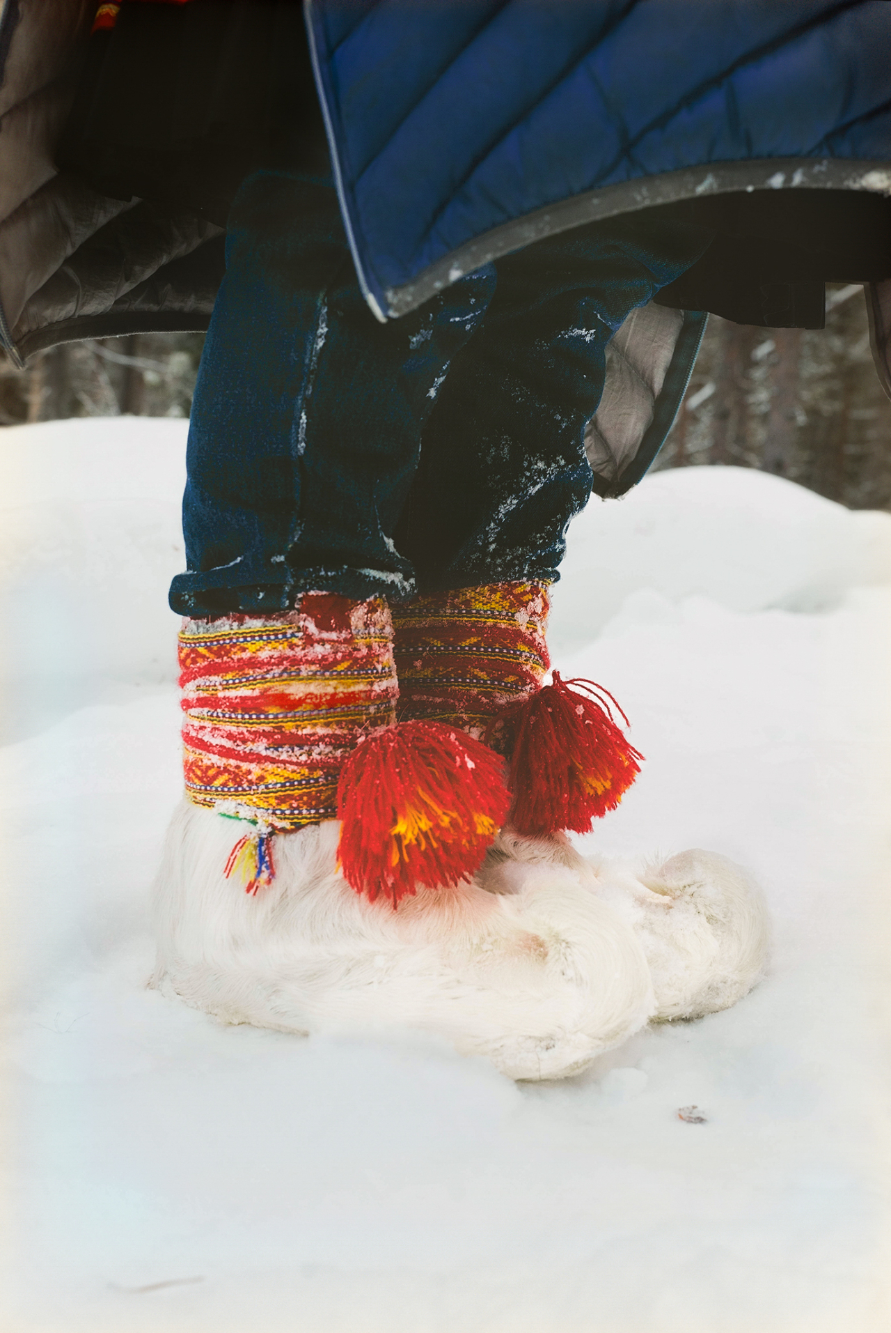 A person wearing snow shoes stands in the hilly snow.