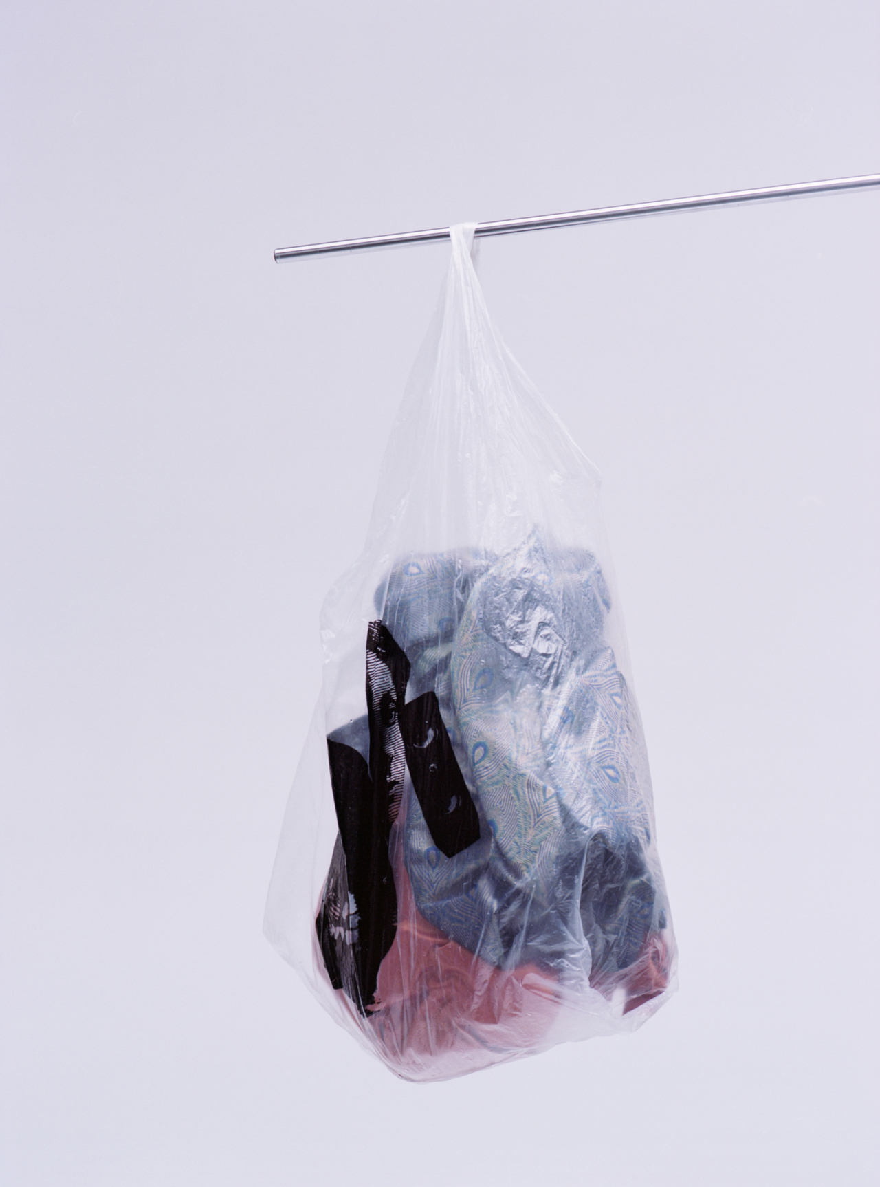 A plastic bag filled with clothing waste hangs from a small metal pole.