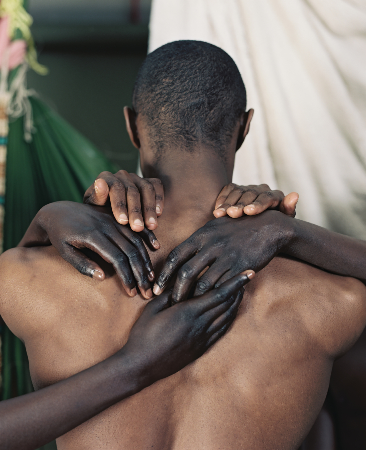 Several black hands grab the neck and back of a shirtless man.