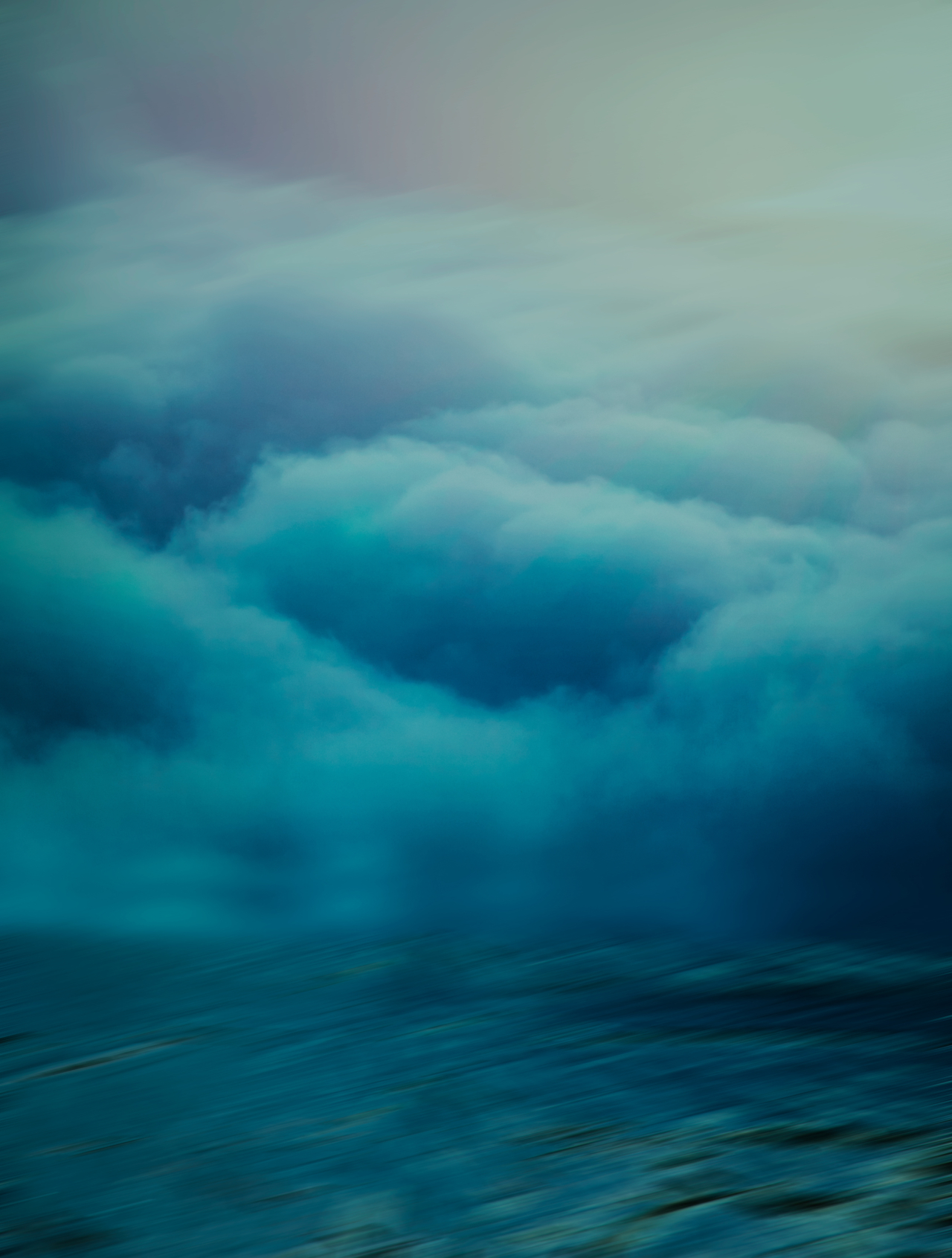 Thick, dark blue clouds swirl above the ocean surface.