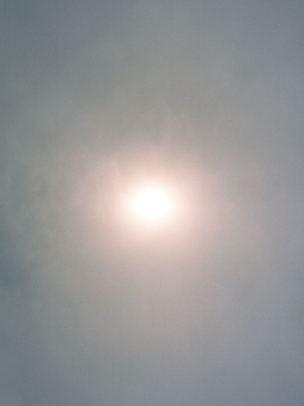 A sun weakly shines through a hazy atmosphere.