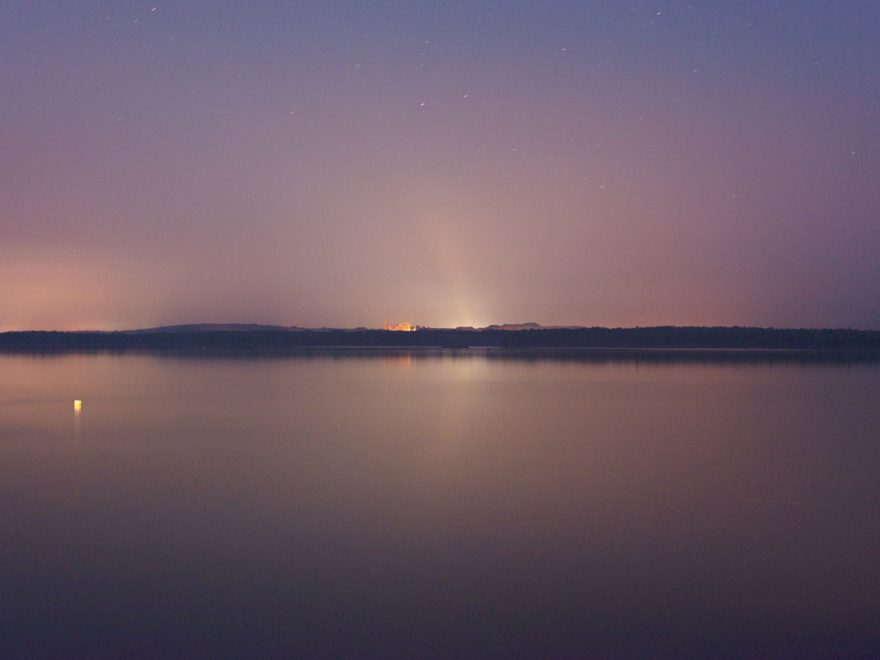 As the sun sets along the water, the sky turns purple.