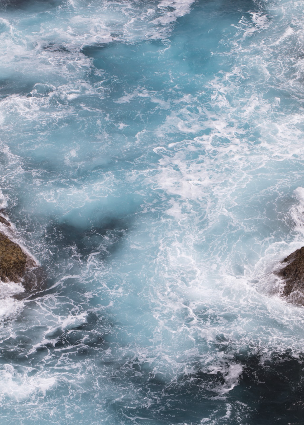 Icy blue waves crash against rocks.