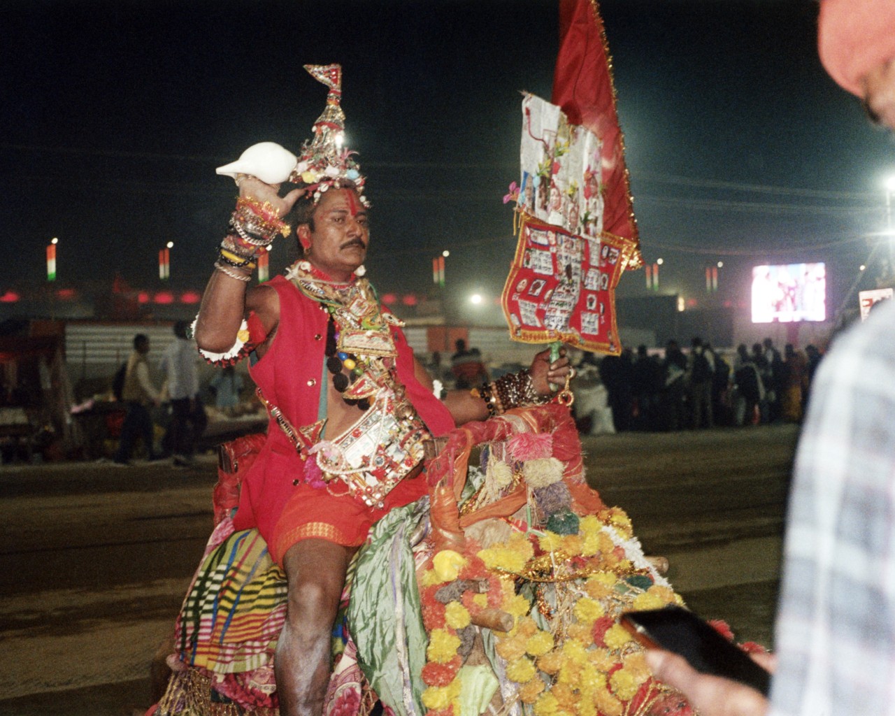A sadhu rides a decorated camel at Kumbh Mela.
