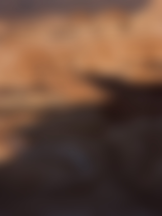 A lone person traverses the paths of a sandy mountain.