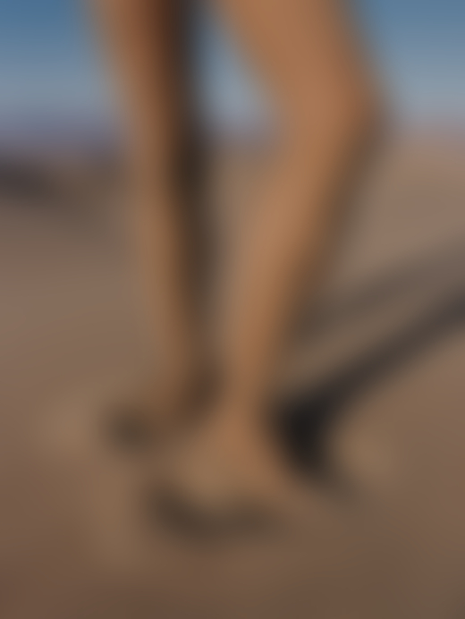 someone's legs are dressed in adorned stockings as their feet sink into the soft sand.