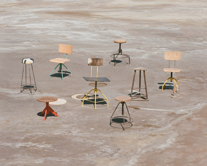 Several chairs sit on a cement surface.