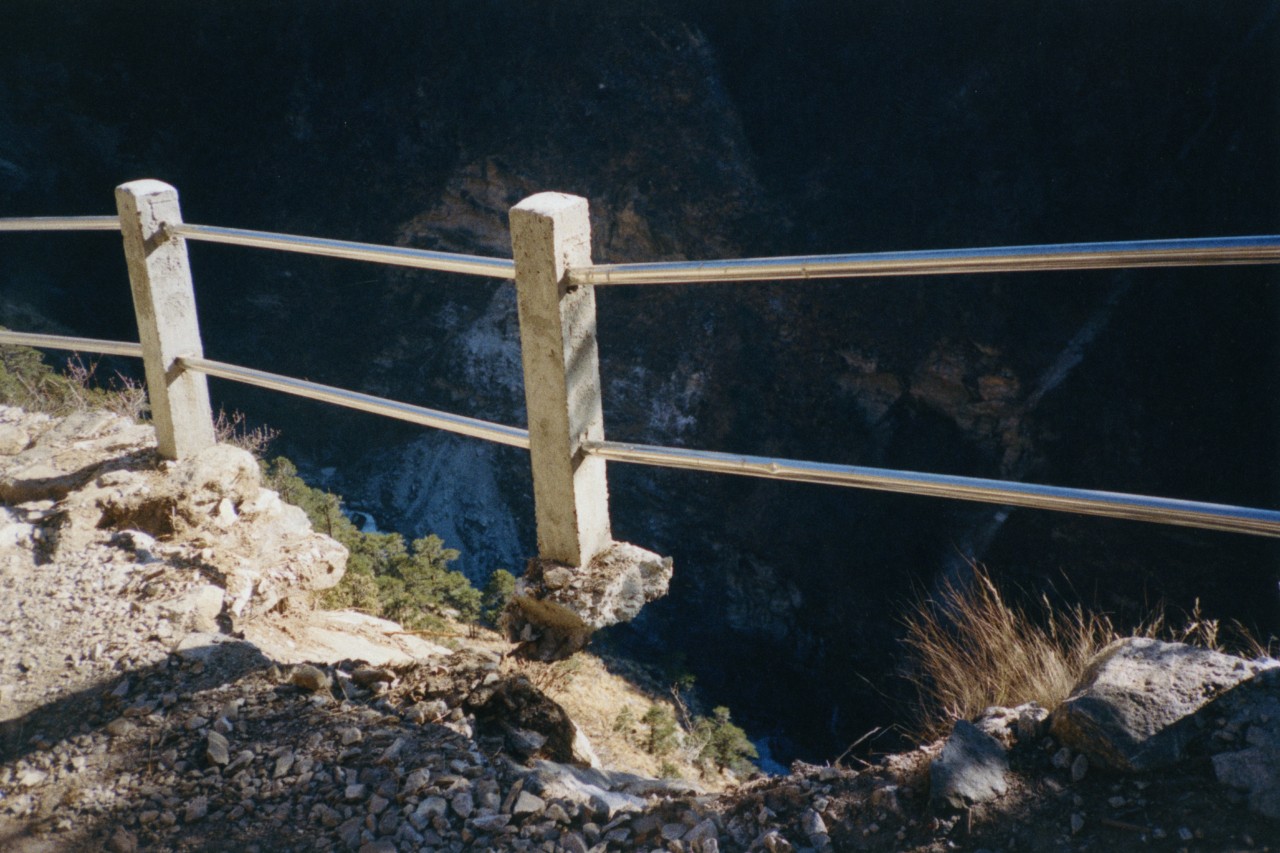 A metal guard railing protects people from the sides of a mountain the Himalayas.