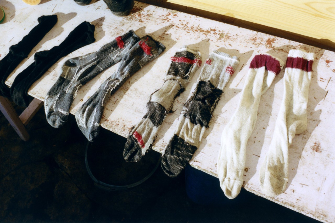 Four pairs of socks lay flat on a piece of white wood.