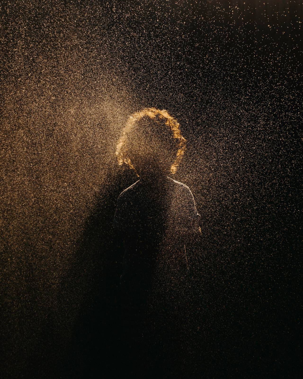 A child stands in the shadows with sparkly light surrounding them.