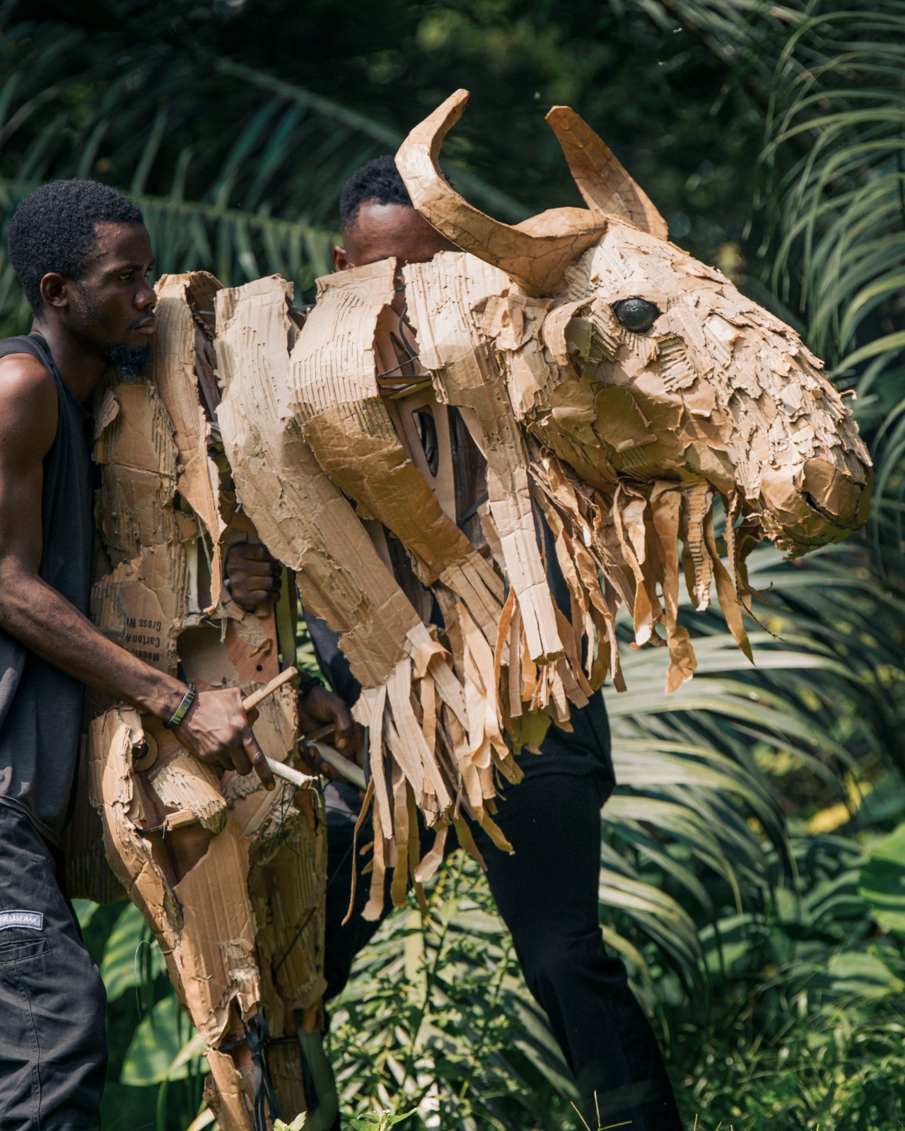 Two men carry a moose animal puppet.