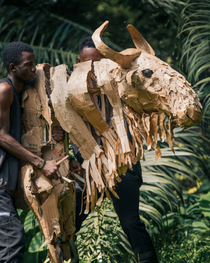 Two men carry a moose animal puppet.