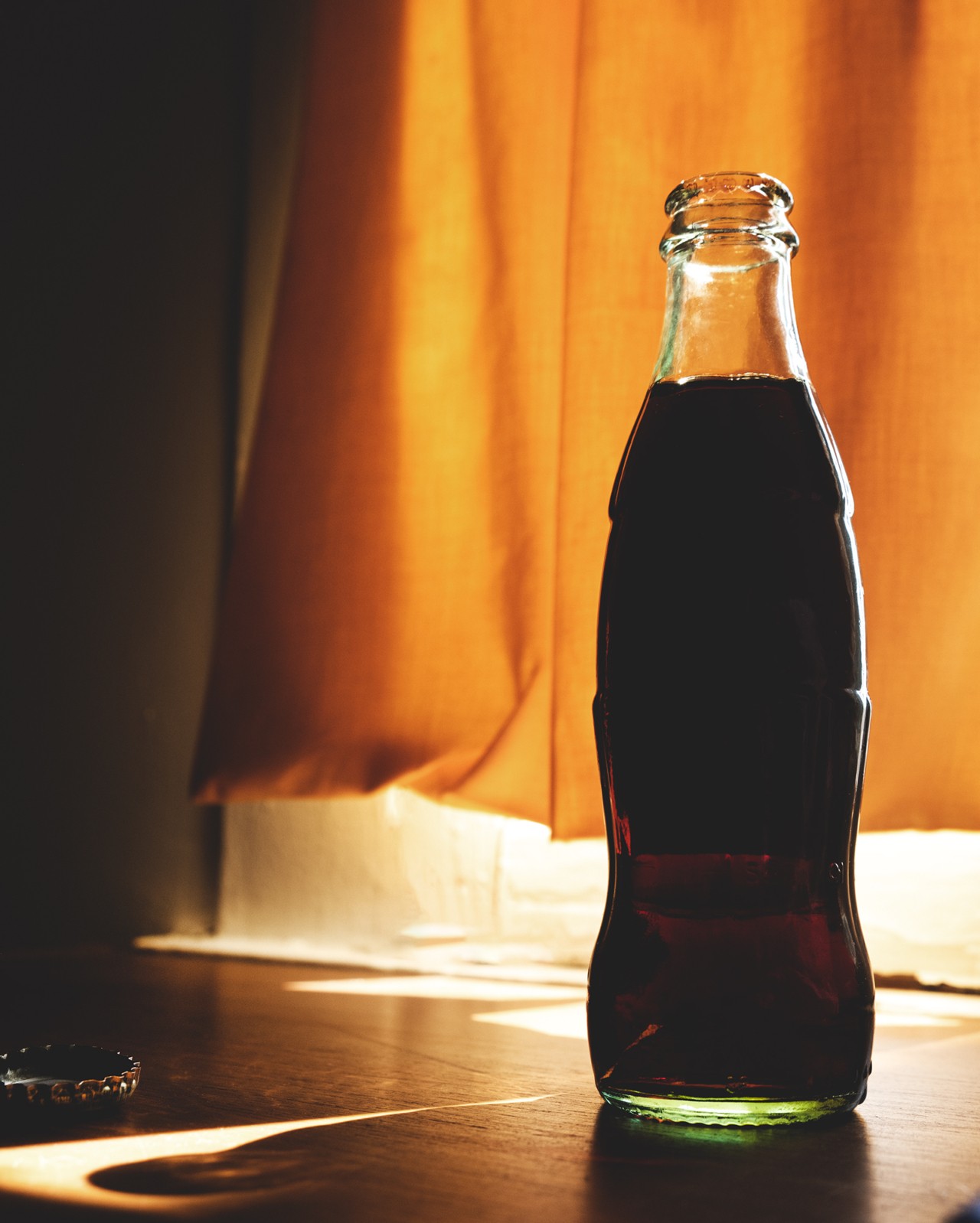 A glass bottle of Gaza cola sits on a brown table.