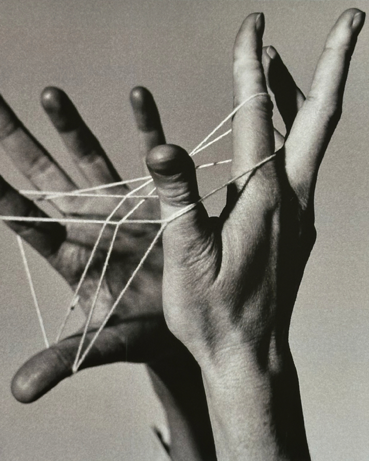 Two hands play a string game.