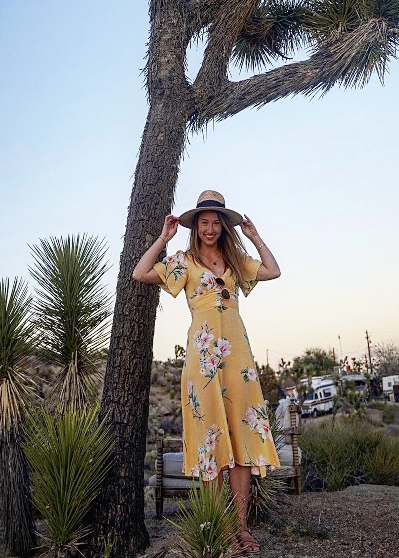 Photo of climate journalist Miranda Green in yellow dress and hat under blue sky.