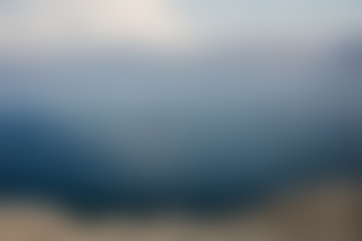 A mountain range lies in the distance of a vast ocean.
