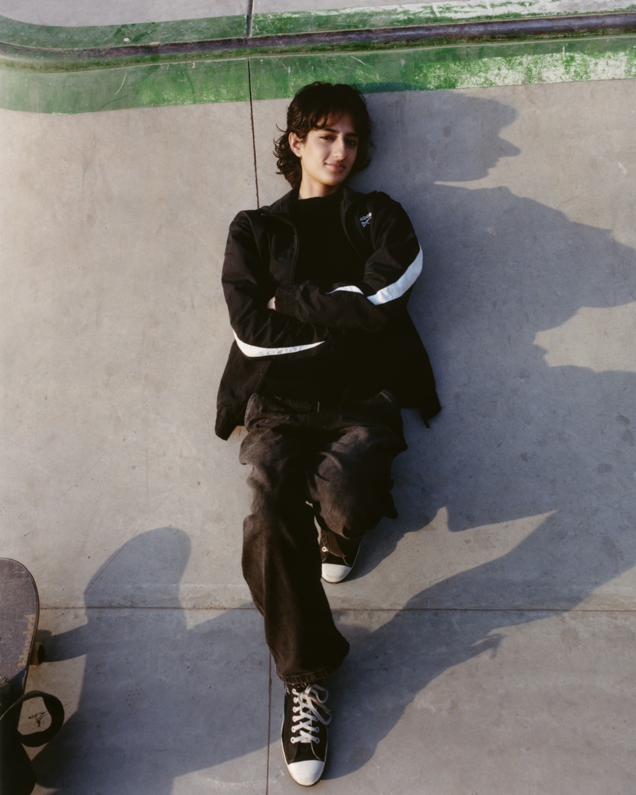 A Pakistani skateboarder lays down in a skatepark.