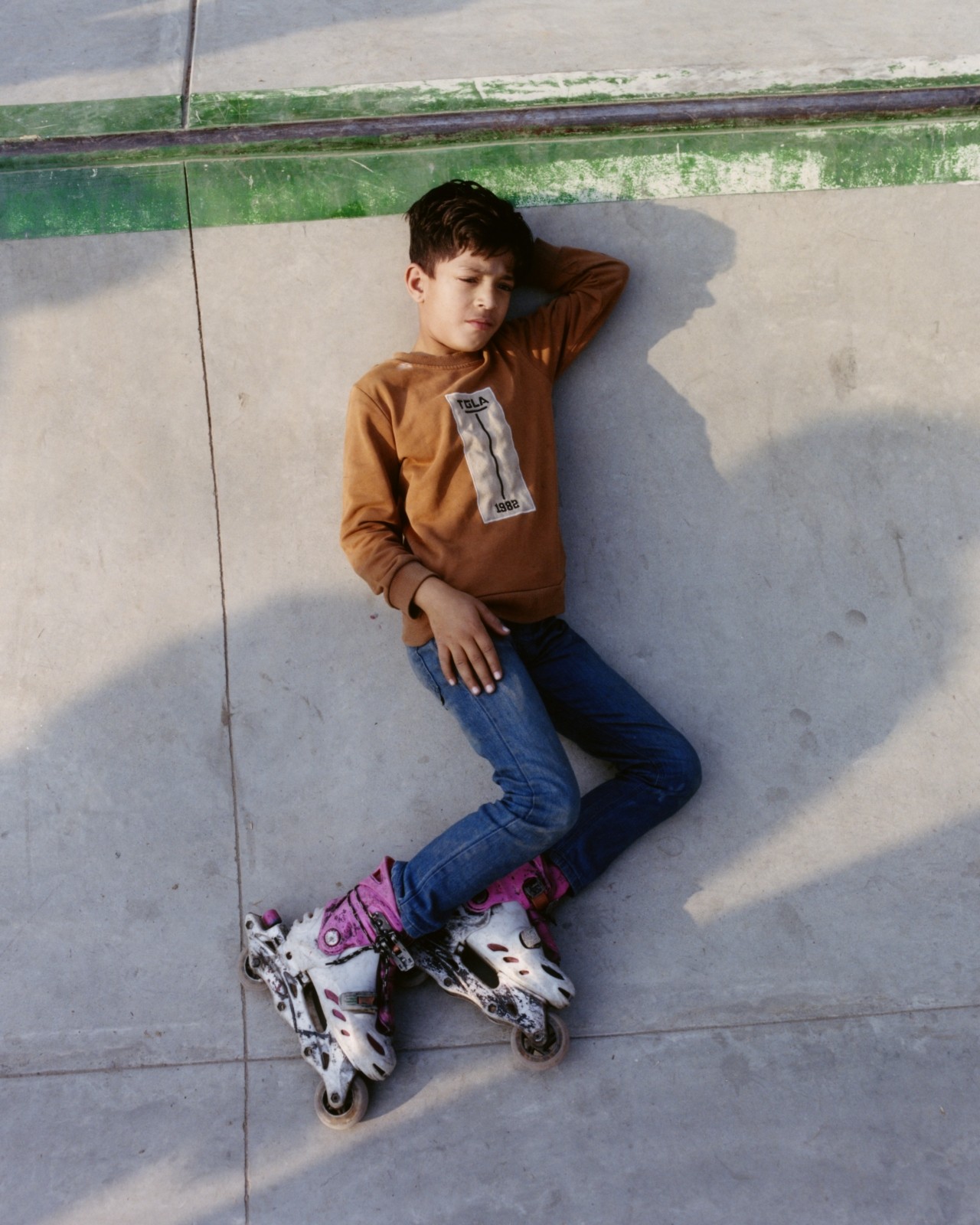 A Pakistani skater lays down in a skatepark.